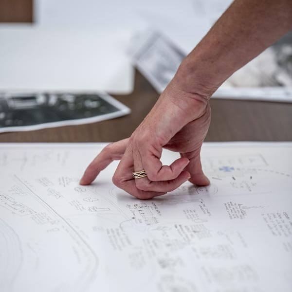 A person's hand pointing at details on a large map.