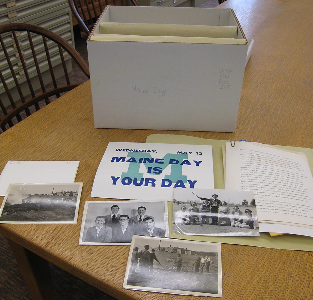 Photographs, open folder, and box arrayed on a table.